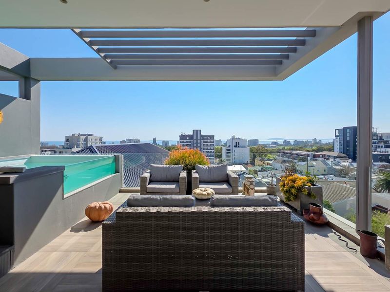 Spacious penthouse balcony featuring a modern pergola, glass balustrade, and a private plunge pool with panoramic city and ocean views.