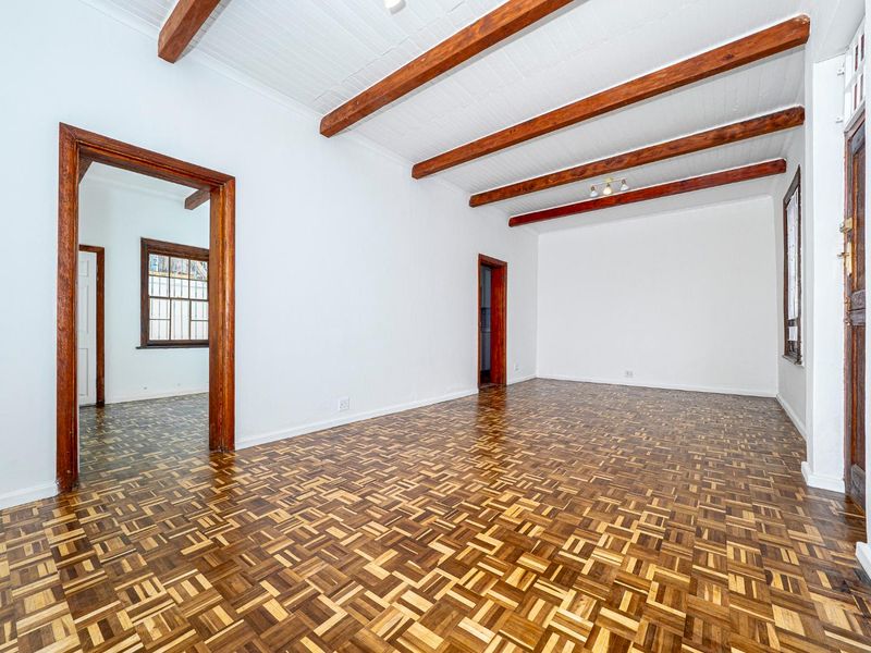 Spacious living area featuring classic parquet flooring, exposed timber ceiling beams, and traditional timber door and window frames.