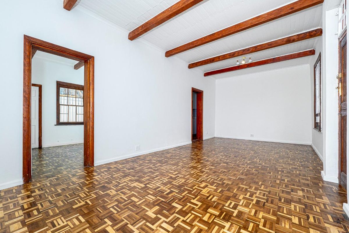 Spacious living area featuring classic parquet flooring, exposed timber ceiling beams, and traditional timber door and window frames.