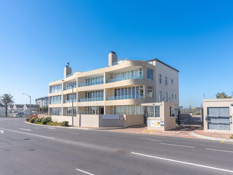 Exterior view of a modern multi-story apartment complex featuring balconies, large glass sliding doors, and a dedicated security gatehouse at the entrance.