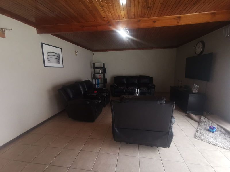 A living room featuring tiled flooring and a timber tongue and groove ceiling.