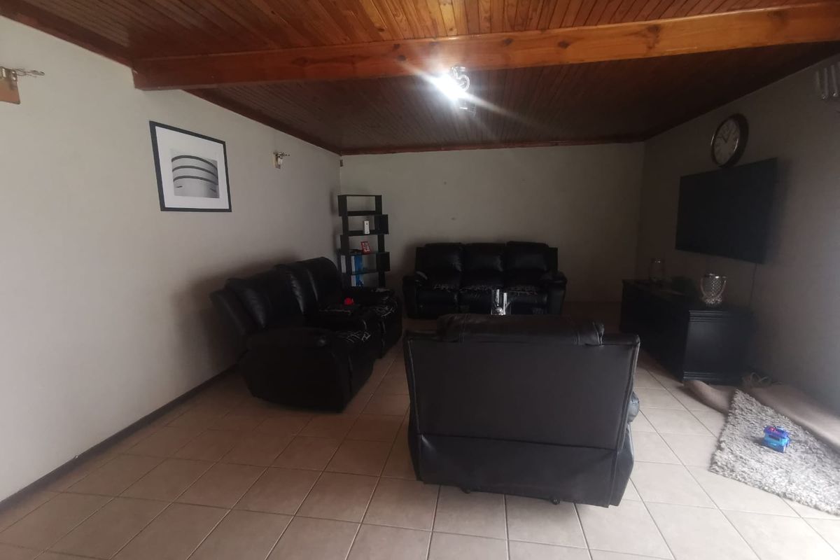 A living room featuring tiled flooring and a timber tongue and groove ceiling.