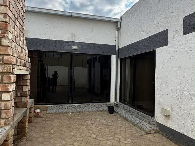 Outdoor patio area featuring a built-in brick braai, paved flooring, and large sliding glass doors providing access to the interior living space.