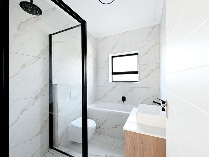 Modern bathroom featuring a walk-in shower with black-framed glass, a built-in bathtub, wall-mounted toilet, and a vanity with a countertop basin.