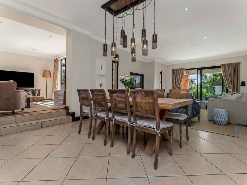Spacious open-plan dining and living area featuring tiled floors, recessed lighting, and large sliding glass doors leading to an outdoor space.