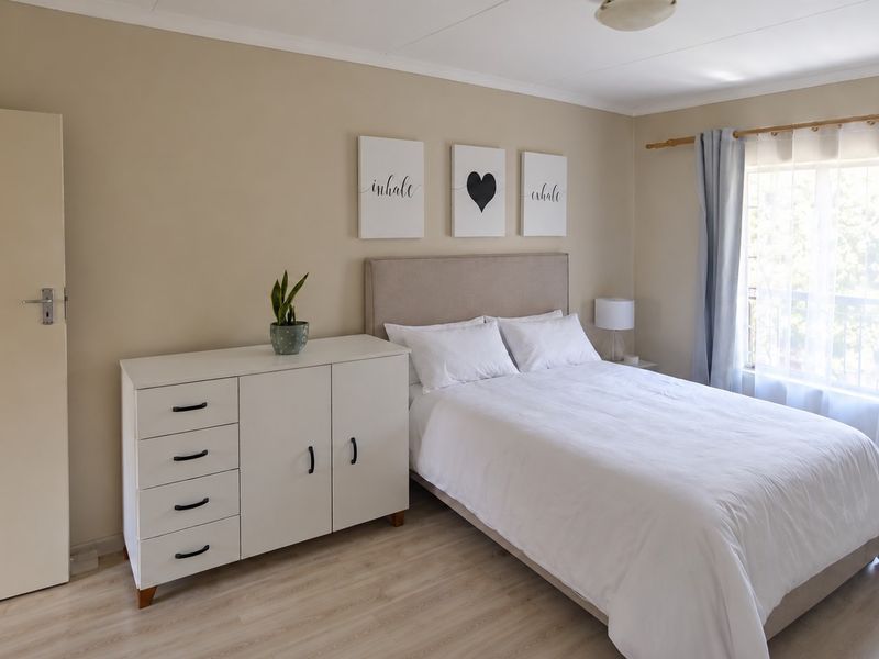 A well-maintained bedroom featuring light-toned laminate flooring and neutral wall finishes, offering a bright and comfortable living space.