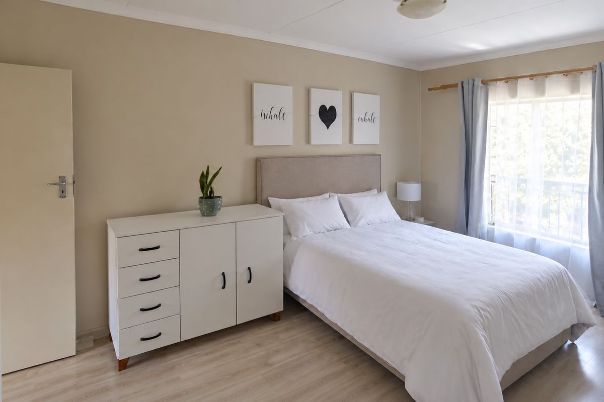 A well-maintained bedroom featuring light-toned laminate flooring and neutral wall finishes, offering a bright and comfortable living space.