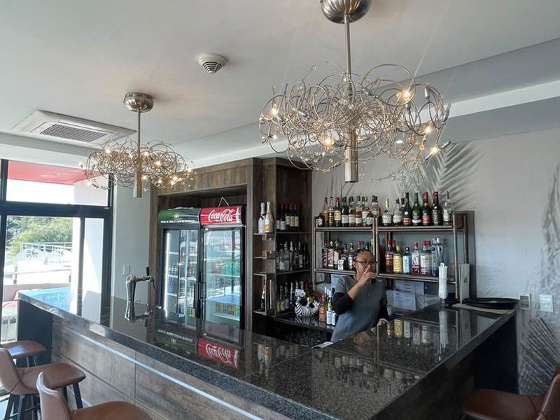 A well-appointed bar area featuring a granite-topped counter, integrated shelving, and modern decorative pendant lighting, suitable for hospitality or entertainment use.