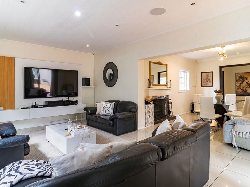 Spacious open-plan living and dining area featuring tiled floors, a built-in media wall, and a classic fireplace, creating a comfortable and functional living space.