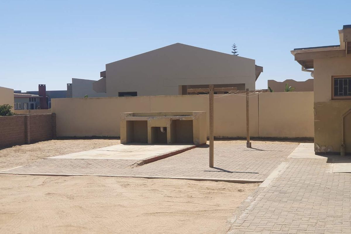 Rear yard featuring a paved area with a built-in masonry braai and a clothesline, set against a perimeter boundary wall.