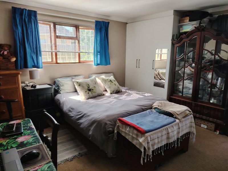 A functional bedroom featuring a built-in wardrobe and a window with security bars, offering a practical layout for a cottage-style home.