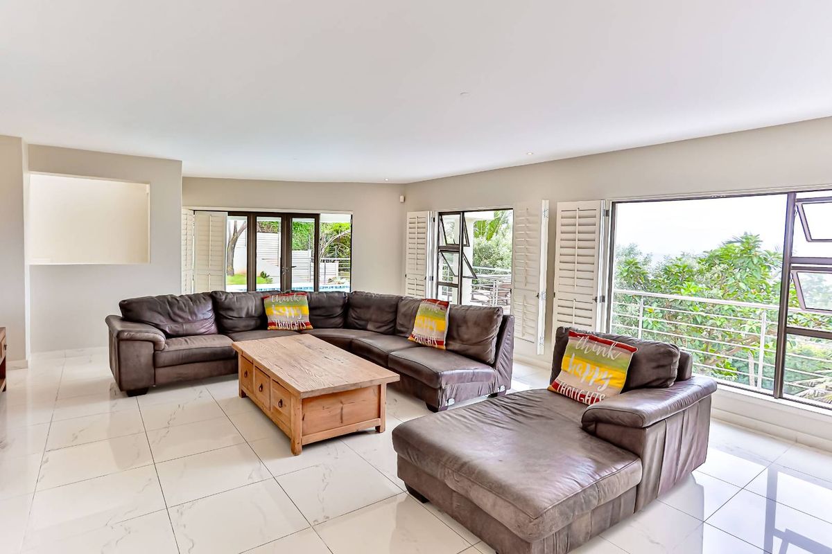 Spacious living room featuring large format tiled flooring, recessed lighting, and multiple glass doors with plantation shutters providing access to the outdoor area.