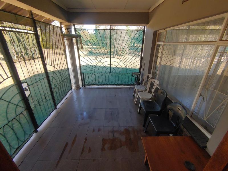 A covered patio area featuring tiled flooring and secure metal gates, providing a transition space between the interior and the garden.