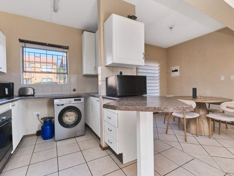 Open-plan kitchen and dining area featuring tiled flooring, built-in cabinetry, a breakfast bar, and integrated oven, offering a functional layout for daily living.