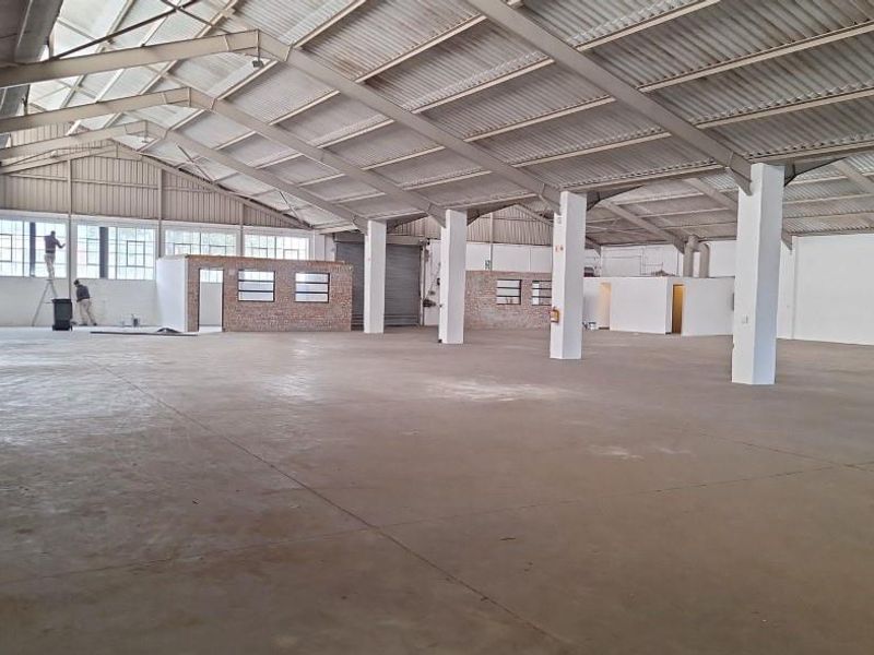Expansive industrial warehouse space featuring high ceilings, steel portal frame construction, concrete flooring, and integrated internal office structures.