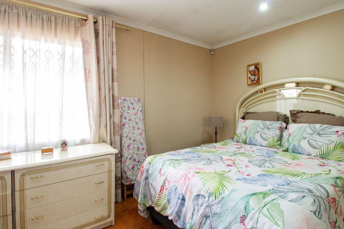 A standard bedroom featuring neutral wall finishes, laminate flooring, and a window with curtain tracks.