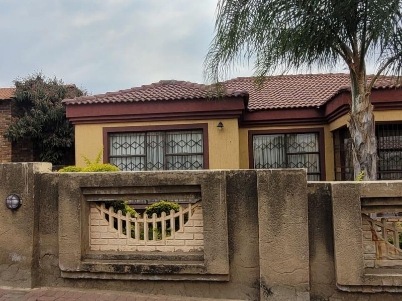 Front view of a residential property featuring a concrete boundary wall with decorative inserts and a tiled roof structure.