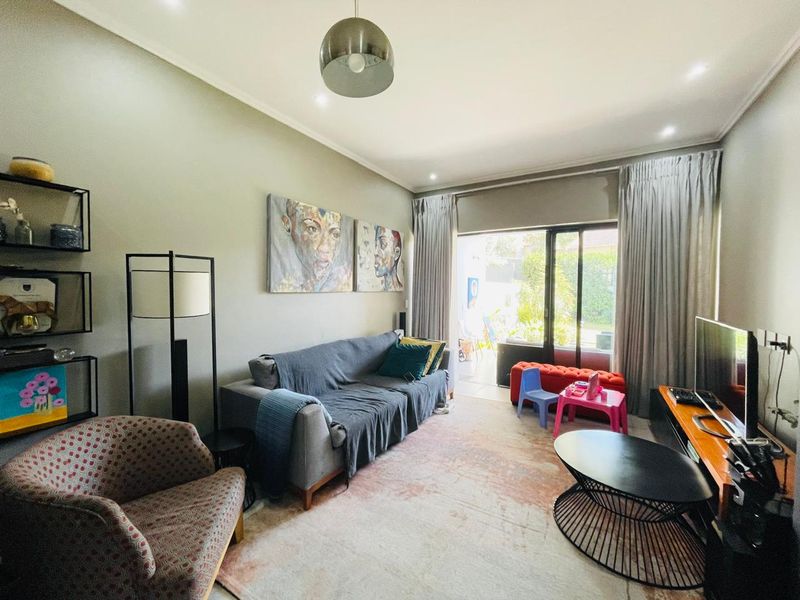A well-lit living room featuring neutral walls, recessed lighting, and large sliding glass doors that provide direct access to the outdoor patio area.