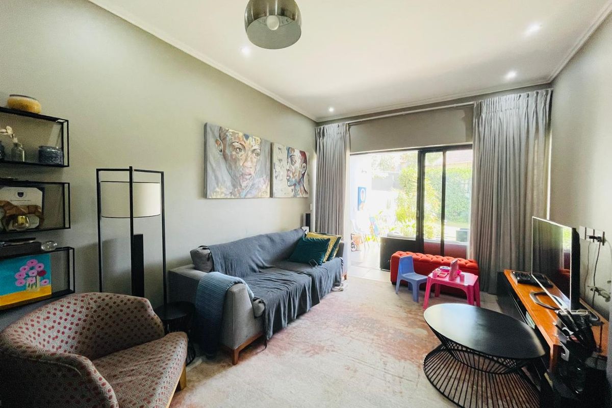 A well-lit living room featuring neutral walls, recessed lighting, and large sliding glass doors that provide direct access to the outdoor patio area.