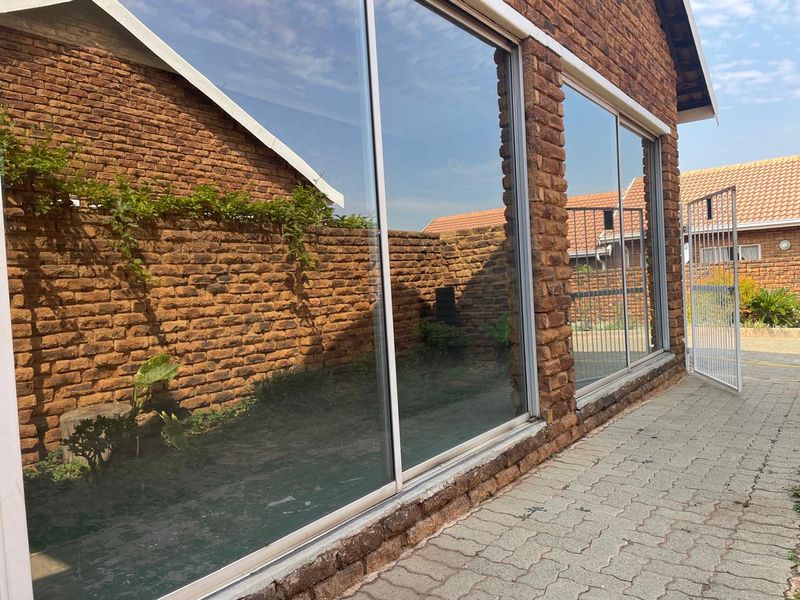 Rear exterior view of the townhouse featuring exposed brick walls, large sliding glass doors, and paved outdoor area.