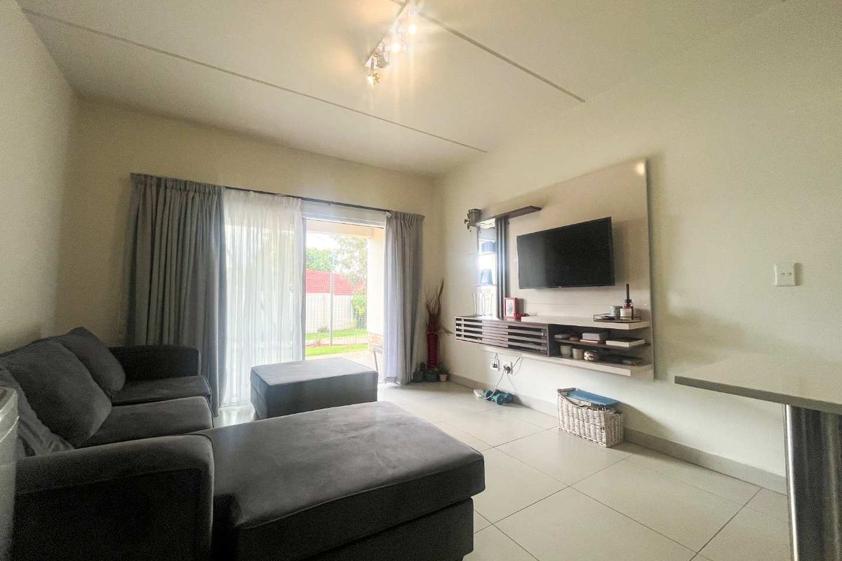 A bright living room featuring tiled flooring, a built-in media console, and a sliding glass door providing access to the outdoor area.