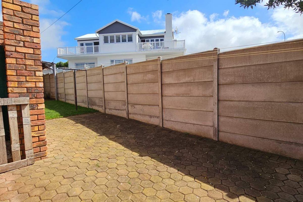 A rear outdoor area featuring a paved patio and a precast concrete boundary wall.