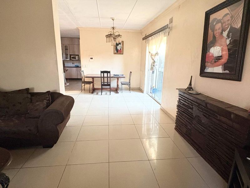 Open plan living and dining area featuring tiled flooring and a sliding glass door, with a view into the adjacent kitchen space.