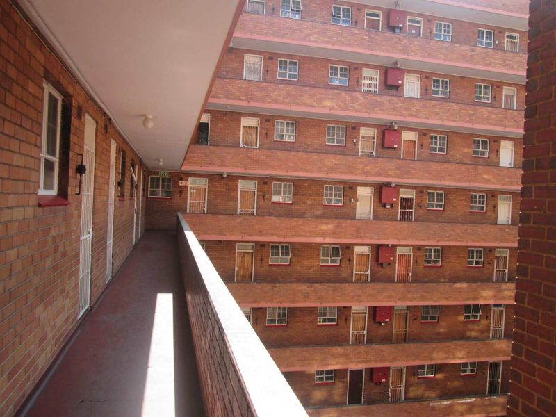Exterior view of a multi-story apartment complex featuring brick facade construction and open-air access walkways.