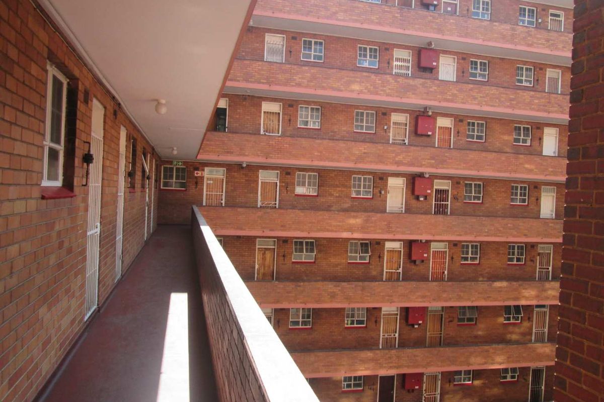 Exterior view of a multi-story apartment complex featuring brick facade construction and open-air access walkways.