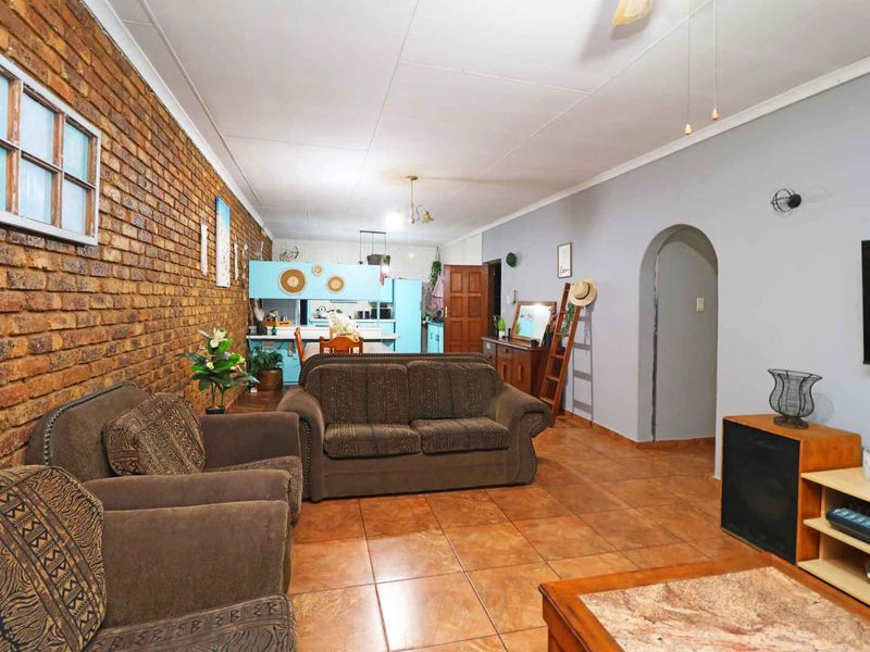 Open-plan living and kitchen area featuring exposed brick walls, tiled flooring, and a classic archway leading to other parts of the home.