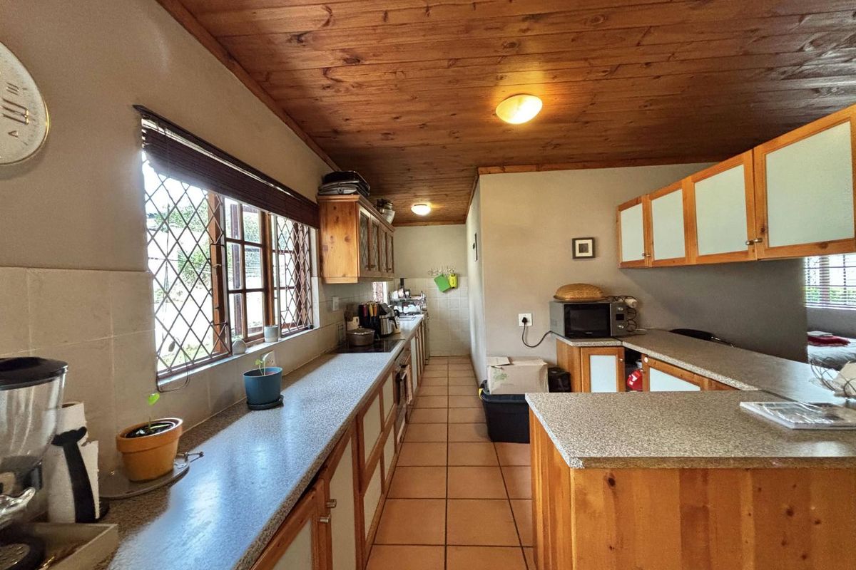 A functional kitchen featuring wooden cabinetry, tiled flooring, and a distinctive wooden ceiling, offering a dated aesthetic with potential for modern updates.