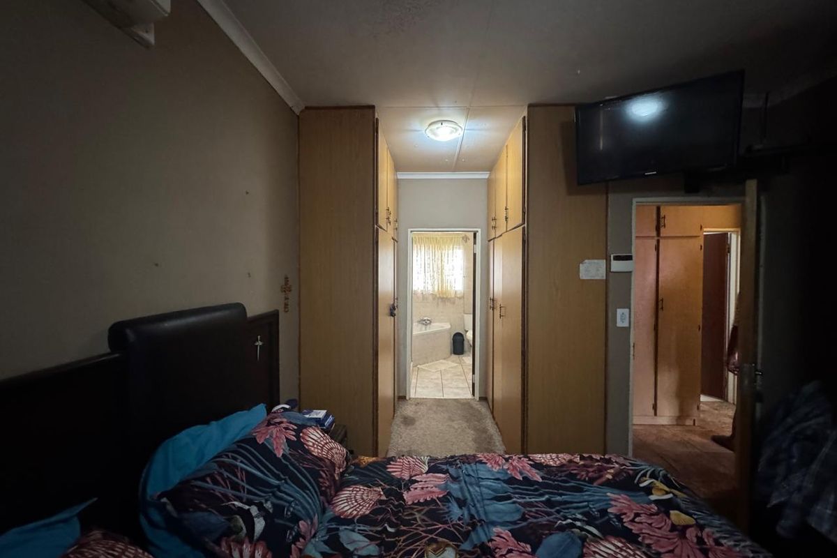 Bedroom featuring built-in wooden wardrobes and direct access to an en-suite bathroom, equipped with a wall-mounted air conditioning unit.