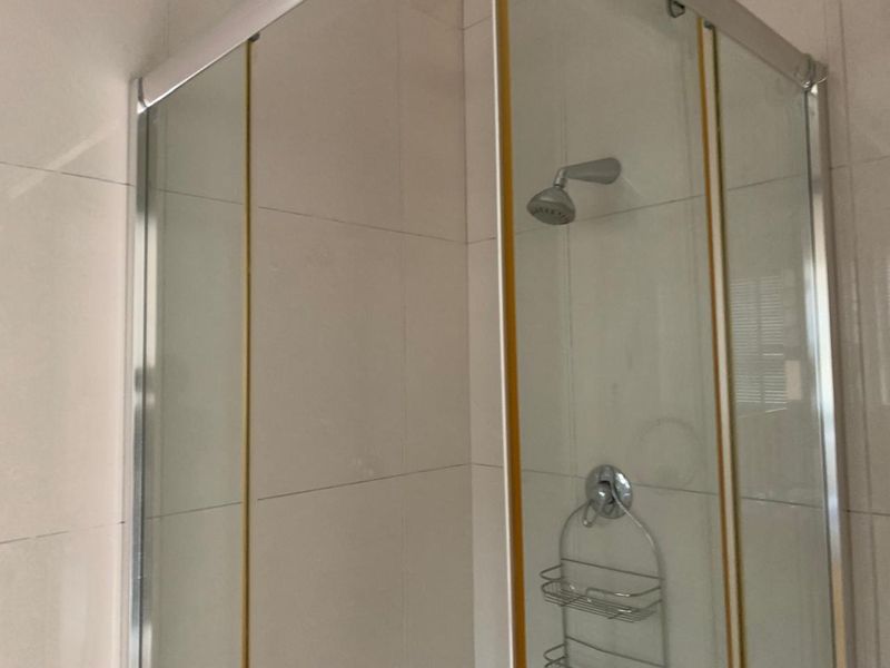 A functional bathroom shower enclosure featuring tiled walls and a standard shower head fixture.
