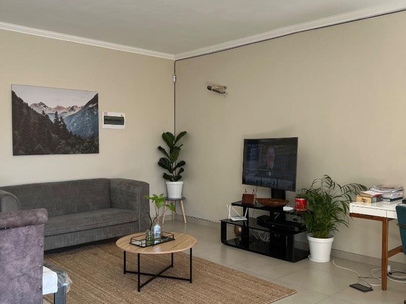 A well-maintained living room featuring neutral tiled flooring, coving, and a modern ceiling light fixture, providing a clean and functional living space.