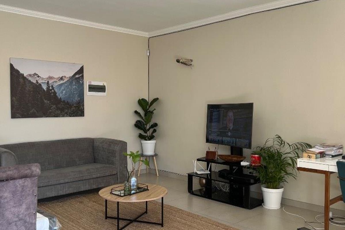 A well-maintained living room featuring neutral tiled flooring, coving, and a modern ceiling light fixture, providing a clean and functional living space.