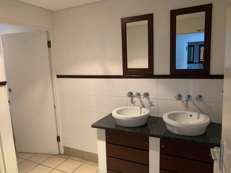 A functional bathroom featuring a double vanity with vessel sinks, granite countertop, wall-mounted faucets, and framed mirrors.
