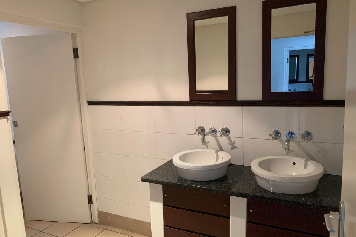 A functional bathroom featuring a double vanity with vessel sinks, granite countertop, wall-mounted faucets, and framed mirrors.