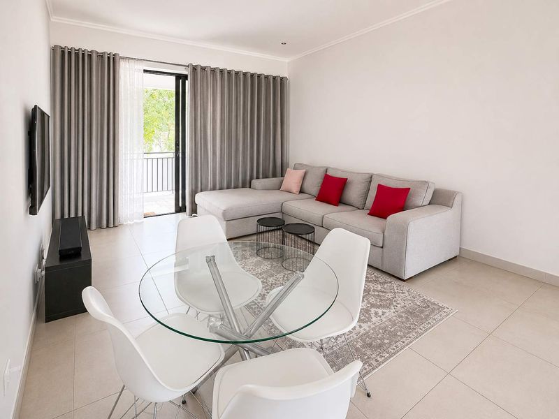 Bright open-plan living and dining area featuring neutral tiled flooring and direct access to a private balcony through sliding glass doors.
