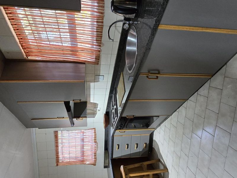 A functional kitchen featuring built-in cabinetry, granite countertops, a stainless steel sink, and tiled flooring with a tiled backsplash.
