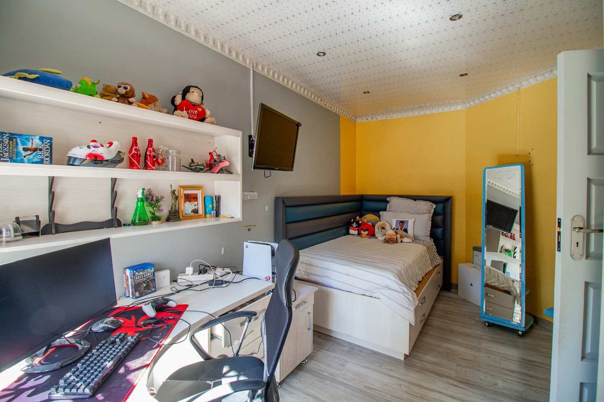 A functional bedroom featuring built-in shelving, a corner bed frame, and recessed ceiling lighting with decorative cornice detailing.
