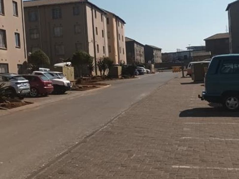 A view of the townhouse complex street and parking area, showing the exterior facade of the residential buildings.
