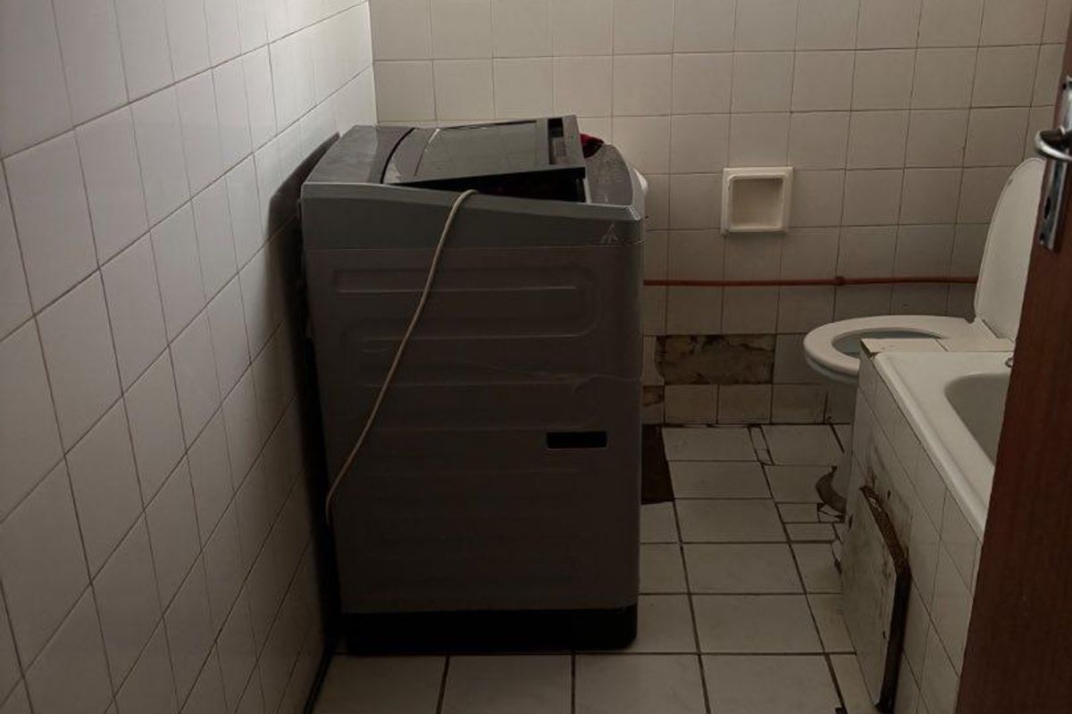 A dated bathroom featuring ceramic tiling, a bathtub, and a toilet, currently showing signs of wear and requiring maintenance or renovation.