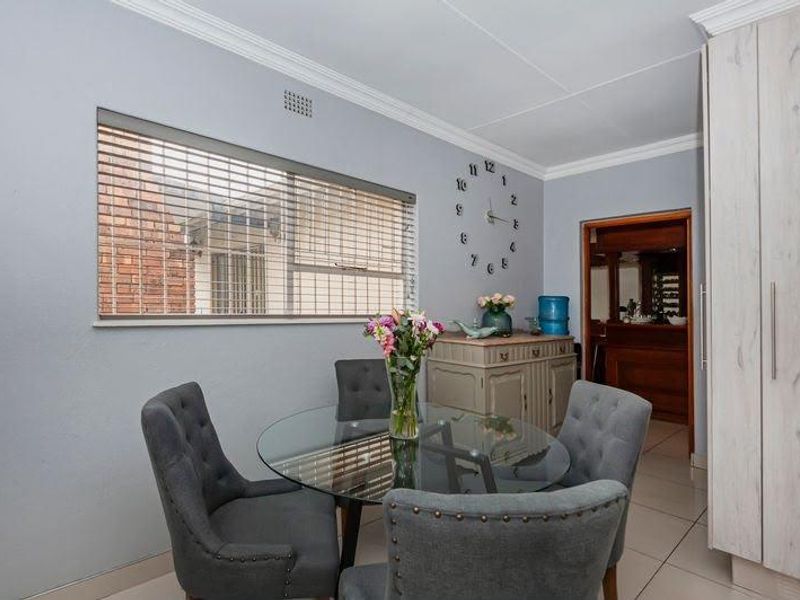 A well-maintained dining area featuring tiled flooring, built-in storage cupboards, and natural light through venetian blinds.