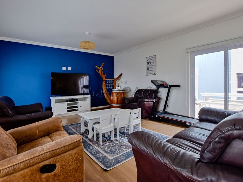 Spacious living room featuring laminate flooring, a bold blue accent wall, and a sliding glass door providing access to the outdoor area.