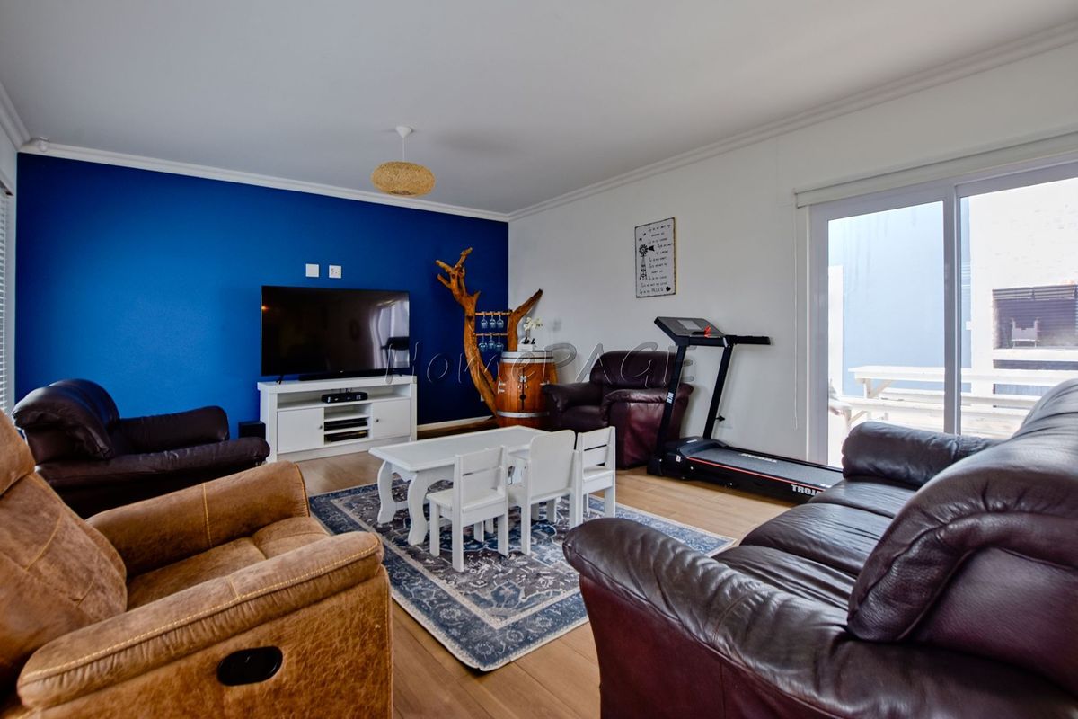 Spacious living room featuring laminate flooring, a bold blue accent wall, and a sliding glass door providing access to the outdoor area.
