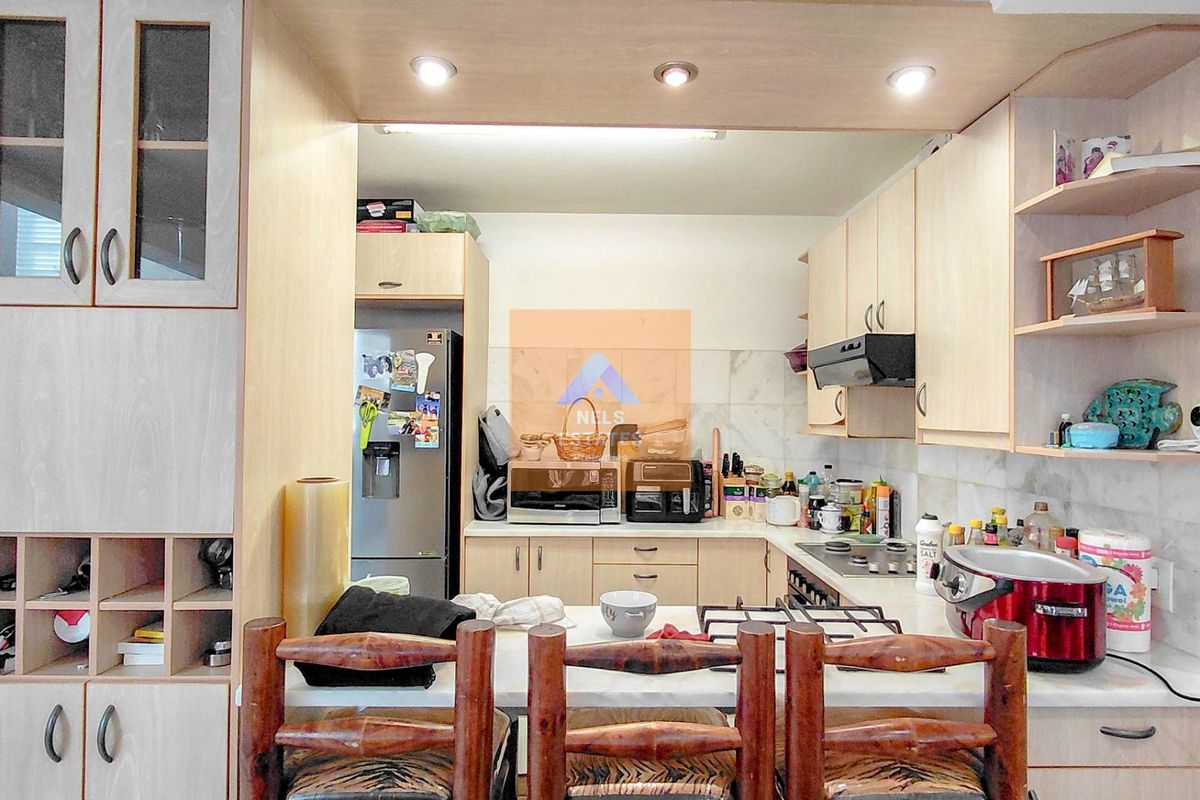 A functional kitchen featuring light wood cabinetry, a breakfast bar, built-in hob, and extractor fan, offering a practical layout for daily meal preparation.