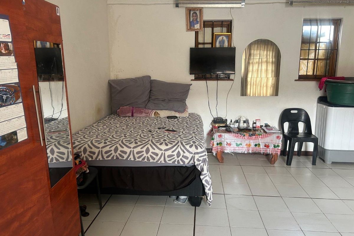 A bedroom featuring tiled flooring, security bars on windows, and built-in ceiling cornicing.