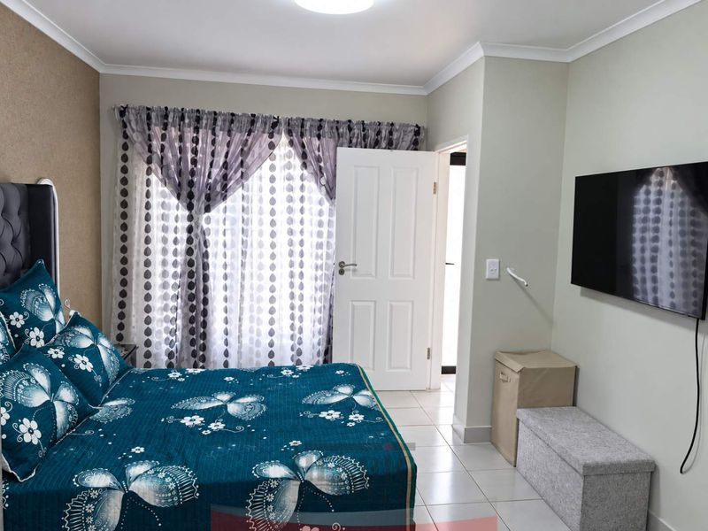 A well-maintained bedroom featuring tiled flooring, neutral wall finishes, and a standard internal door leading to an adjacent space.