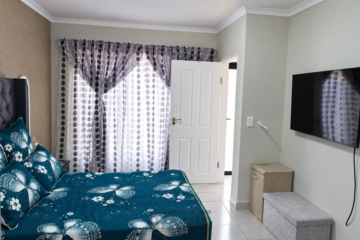 A well-maintained bedroom featuring tiled flooring, neutral wall finishes, and a standard internal door leading to an adjacent space.