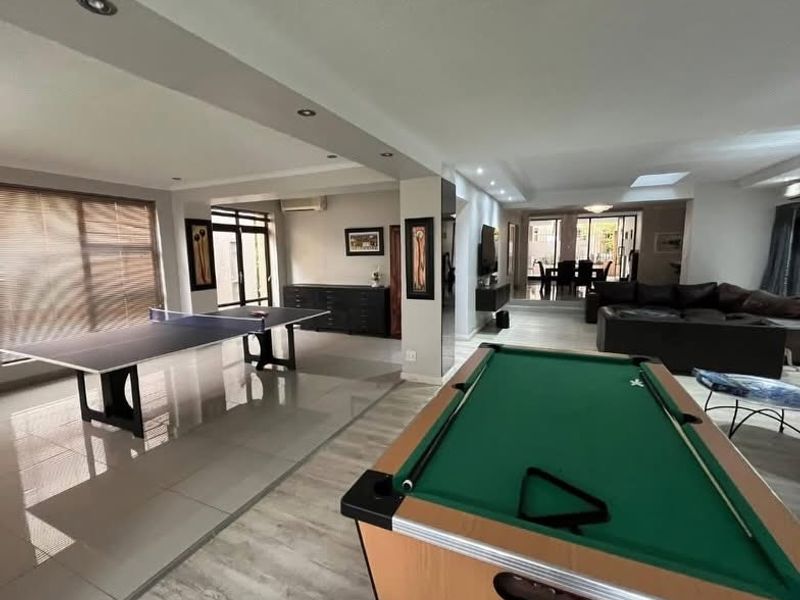 Spacious open-plan living area featuring a mix of tiled and laminate flooring, recessed lighting, and seamless flow to the outdoor patio area.
